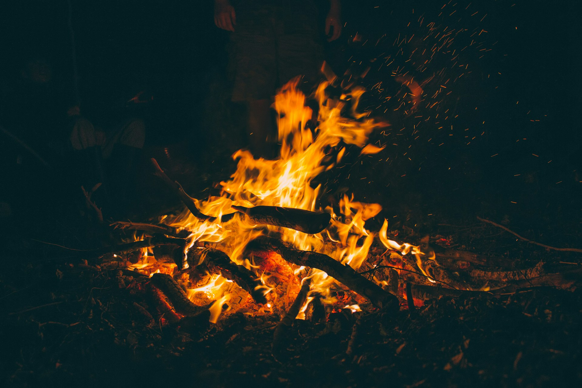 Three Middle-Aged Men Telling Scary Stories Around A Campfire